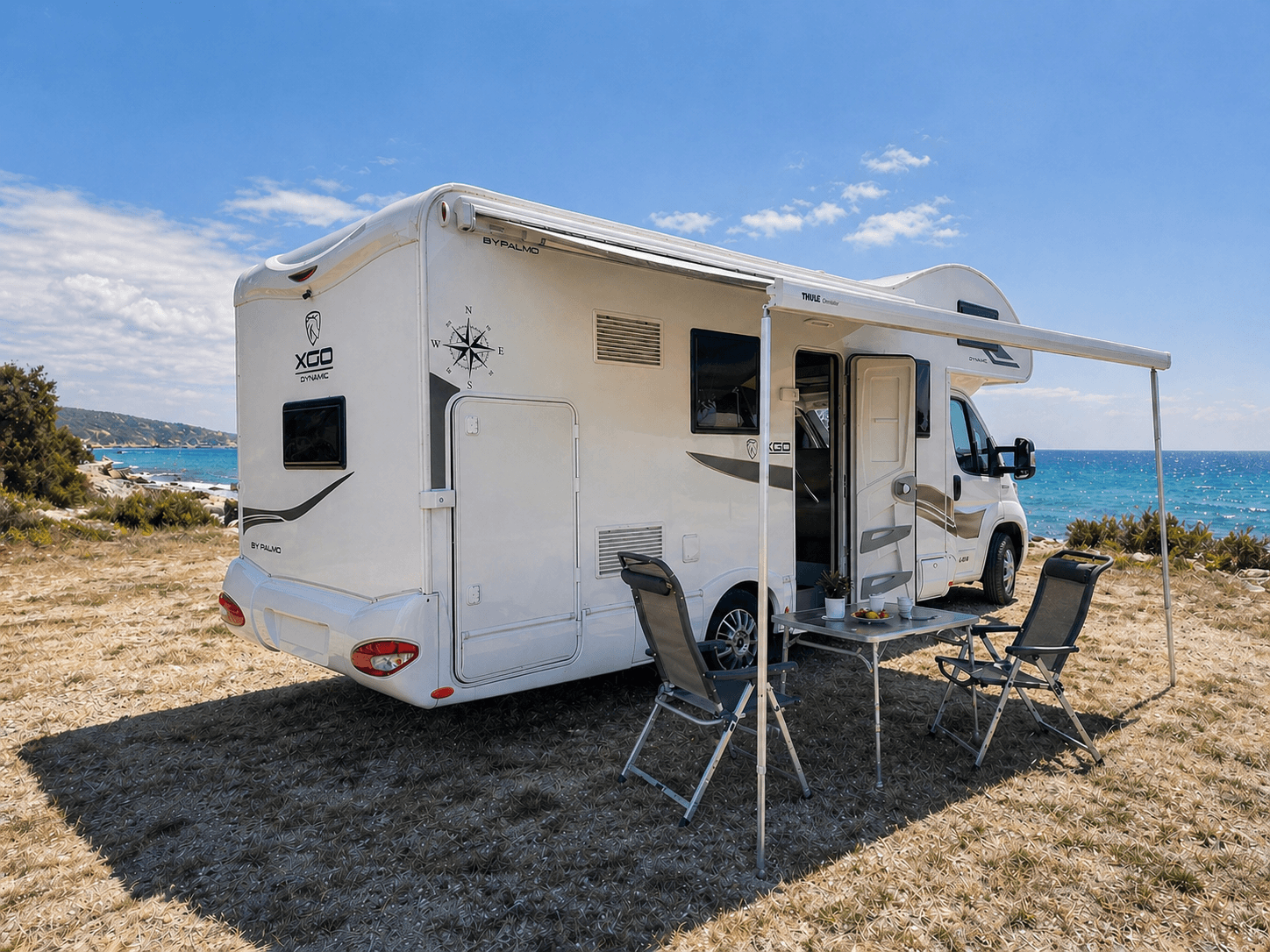 Voyago Cruiser Wohnmobil mit ausgefahrener Markise, Tisch und Stuehlen im Freien