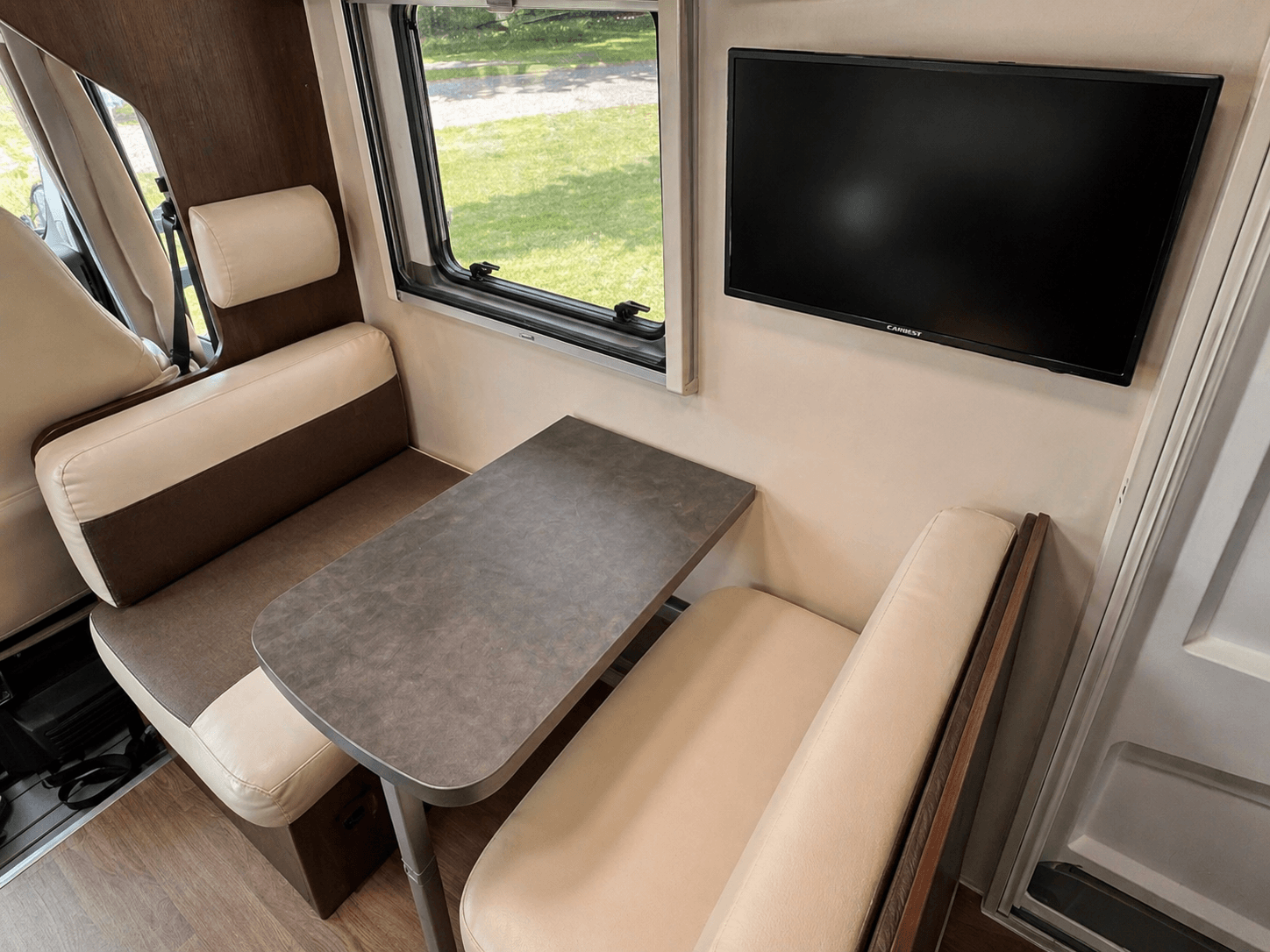 Essbereich im Wohnmobil mit Tisch und wandmontiertem Fernseher