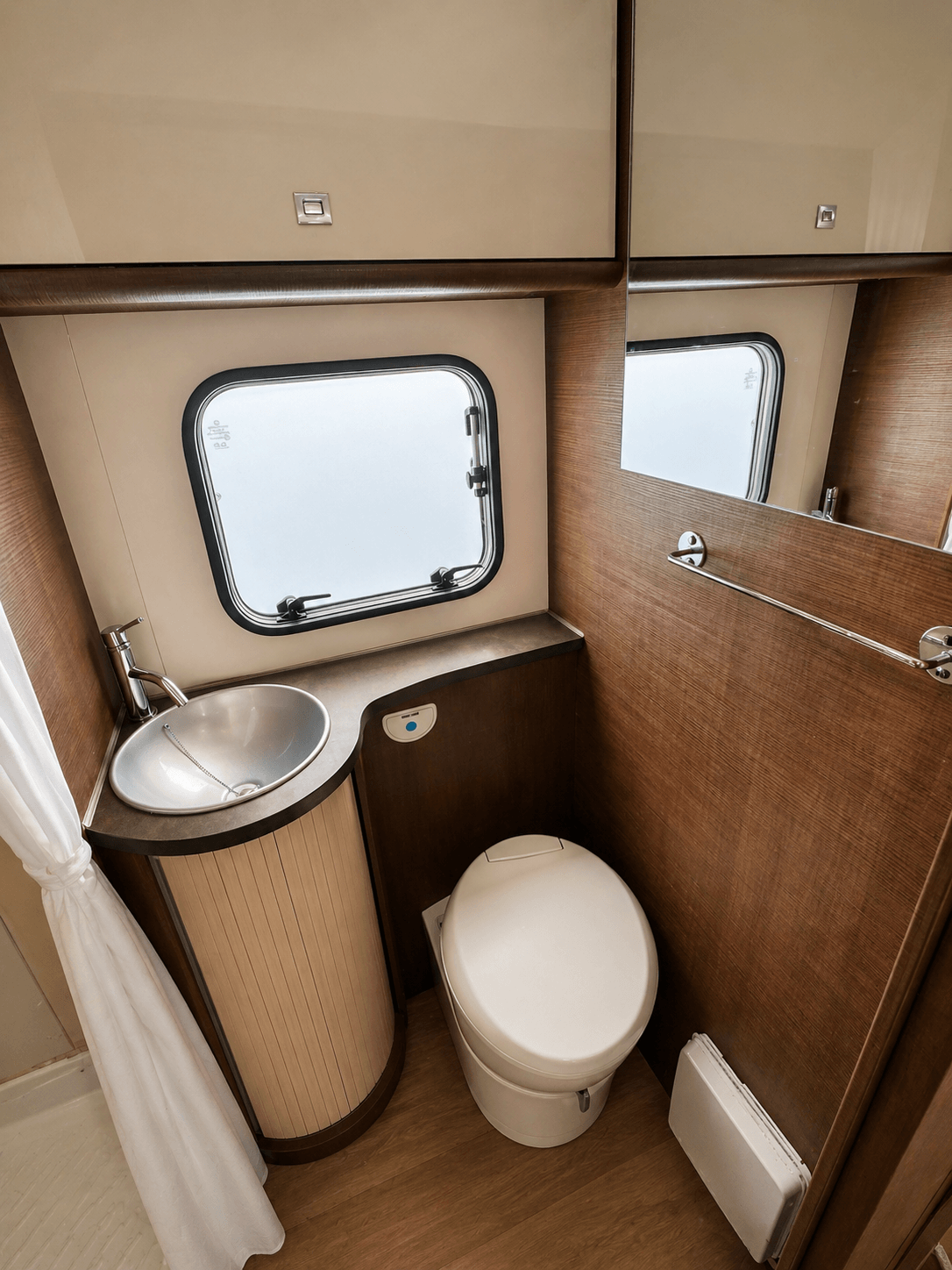 Toilettenbereich im Wohnmobil mit WC, Spiegel und Waschbecken